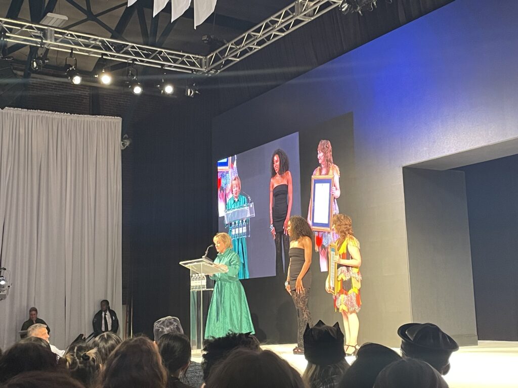Thomas Jefferson University President Dr. Susan C. Aldridge (left), along with Fashion Design Interim Program Director Carly Kusy (right), award alumna Alicia Pinckney (c/o 2013) the Fashion Design Alumna of the Year award; photo © 2025 Manic Metallic 